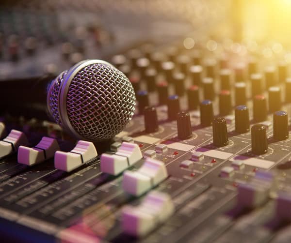 Image of Microphone resting on a sound console in a recording studio