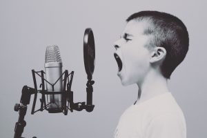 Black and white photo of child shouting into a microphone by Jason Rosewell on Unsplash