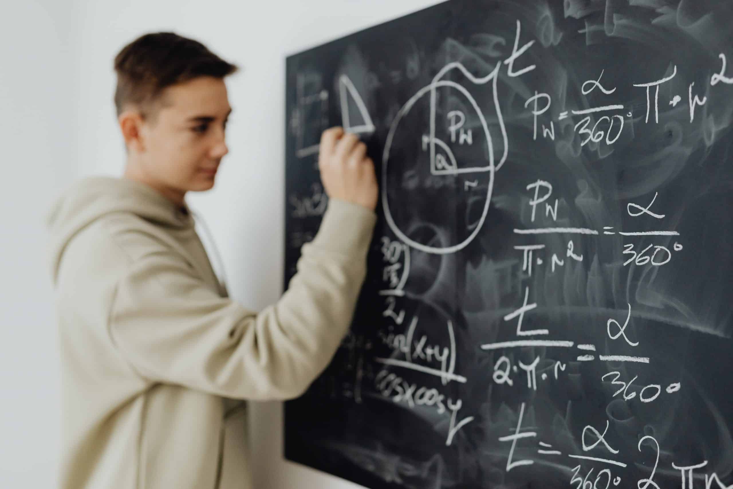 A student writing complex maths on a blackboard