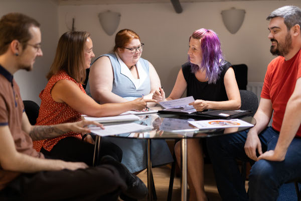 Susie and several A2i team members exchanging ideas and smiling in a meeting.