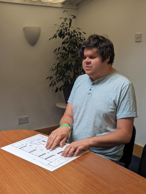 Dave sitting at a meeting table, reading a tactile map.