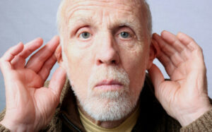 Deaf man putting his hands to his ears to indicate that he can not hear