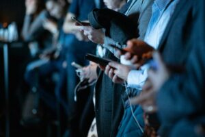 several people using their smartphones, some connected to earphones